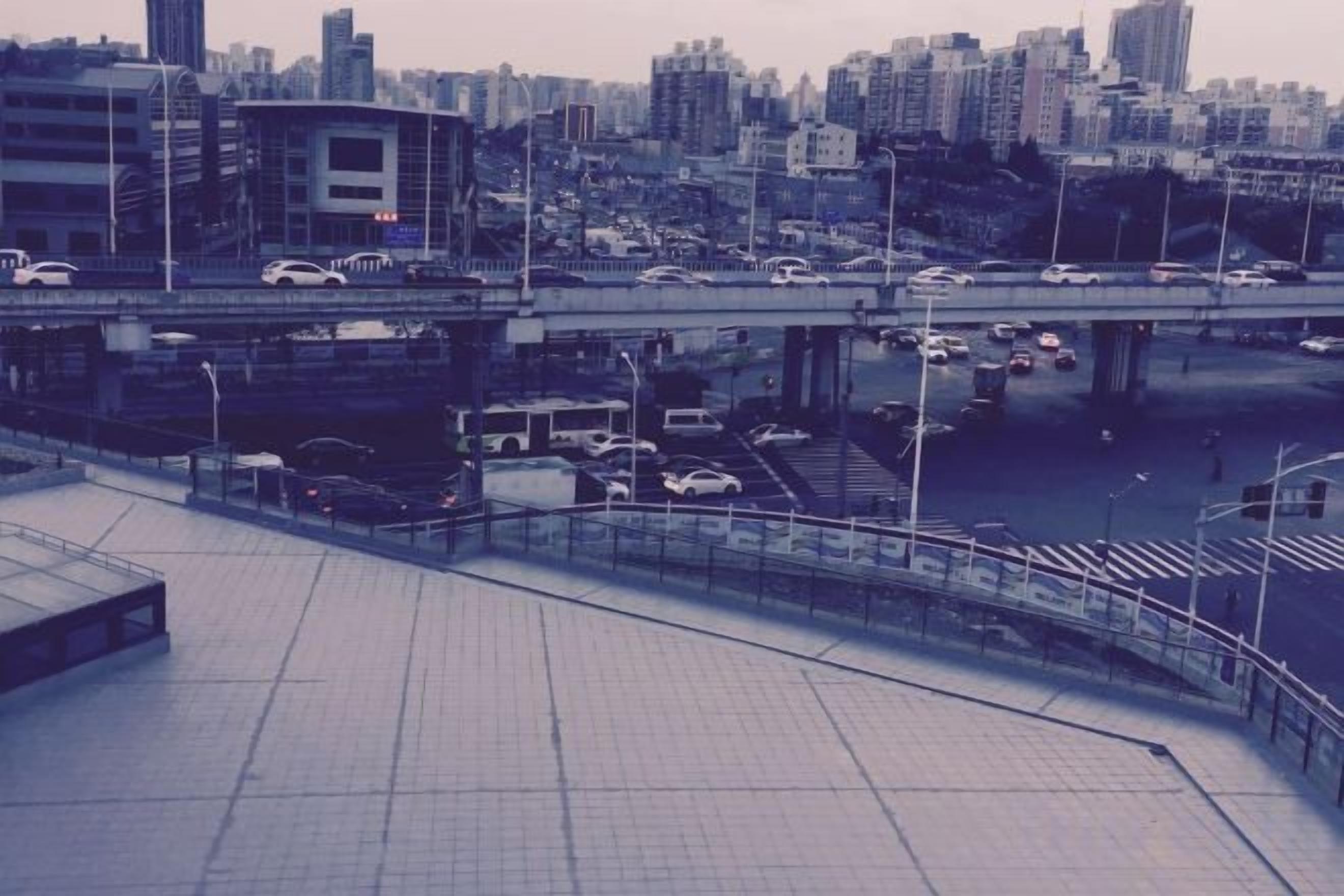 A cityscape with a bridge, vehicles, and a pedestrian walkway.