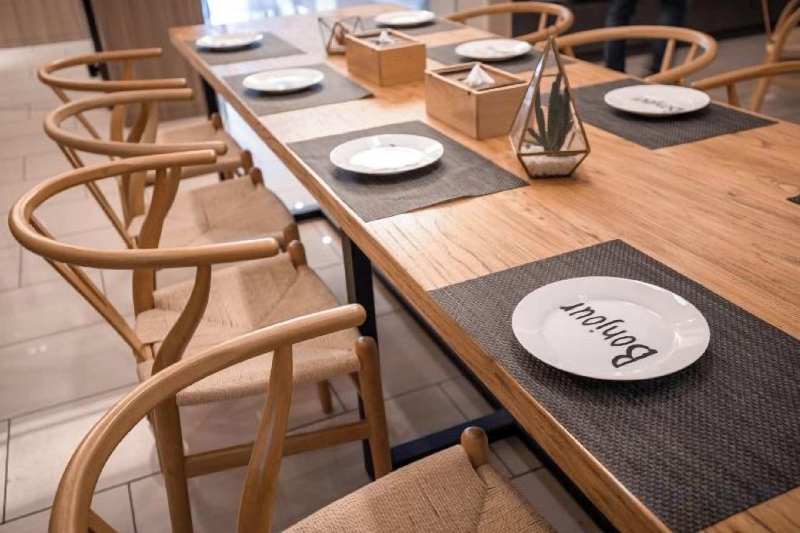 A dining table with chairs, plates, and a candle centerpiece.