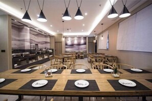Uma sala de jantar ampla, com várias mesas e cadeiras, iluminação pendente e design de interiores moderno.