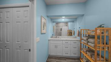 A hallway with a bathroom featuring a sink, mirror, and towel rack.
