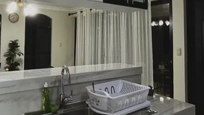 A kitchen with a sink, a dish rack, and a mirror above the counter. - Residencia Cálida y acogedora (Santa Tecla)