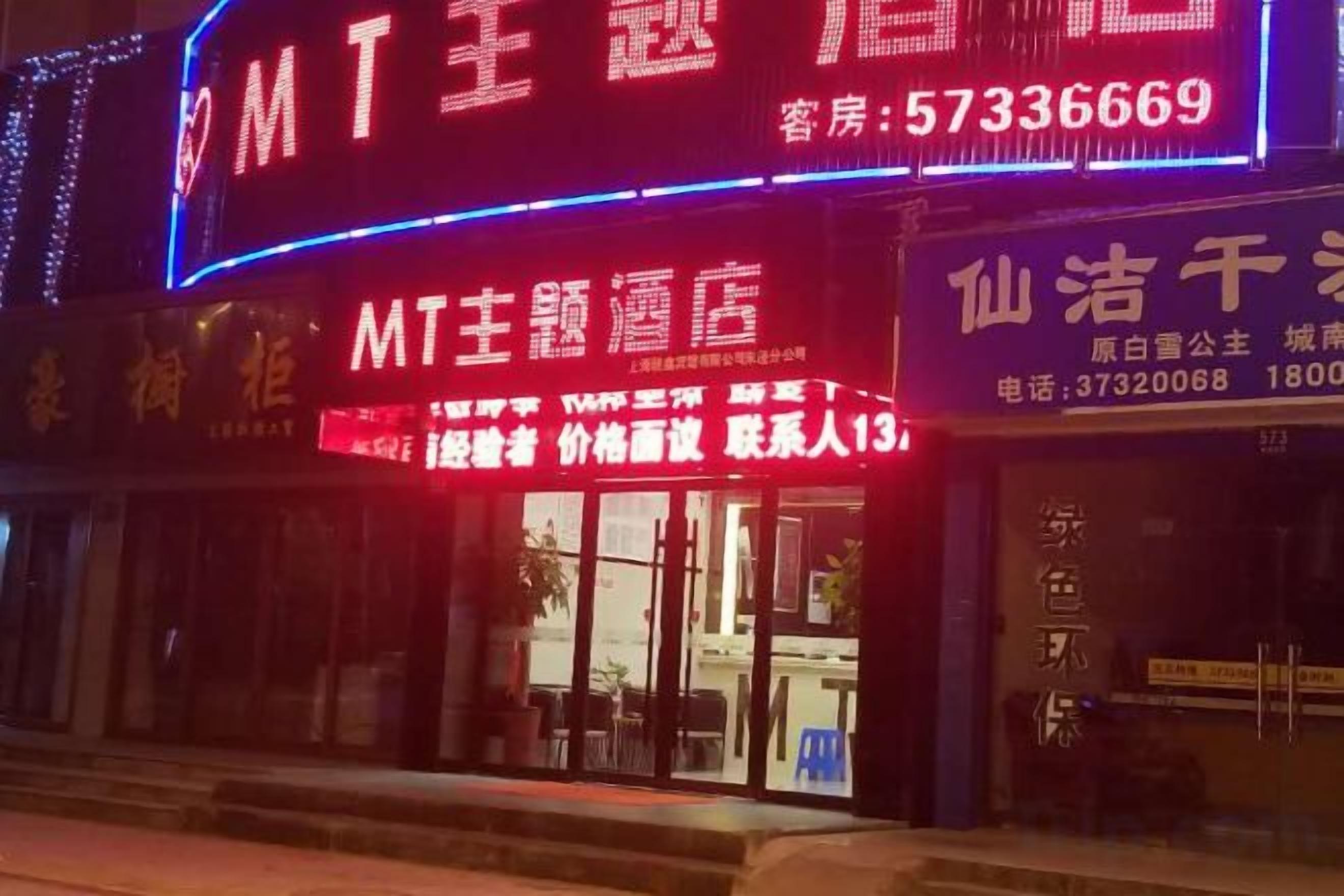 A hotel with illuminated signage, a visible entrance, and a clear view of the reception area.
