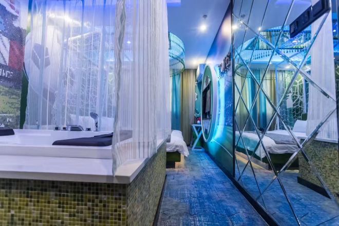 A modern hotel room with a large bathtub, a separate shower area, and a glass partition.