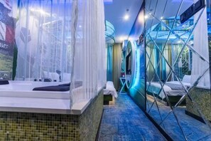 Habitación de hotel moderna con una bañera grande, zona de ducha separada y un separador de vidrio.