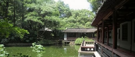 A traditional building with a waterway in front, surrounded by lush greenery.
