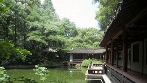 A traditional building with a waterway in front, surrounded by lush greenery. - Mt Theme Hotel Shanghai (Shanghai)