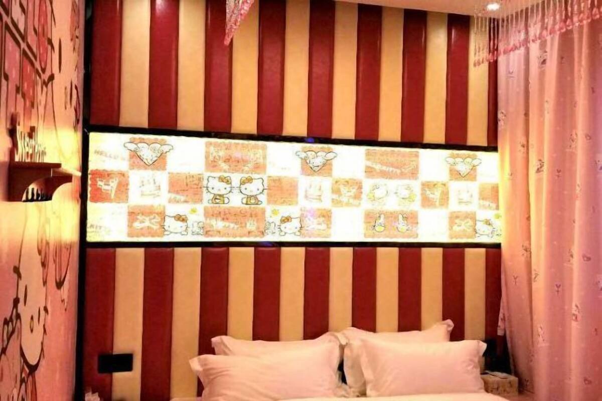 Una habitación con pared a rayas, una cama con almohadas y un panel decorativo con personajes de dibujos animados.