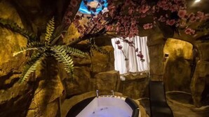 A hot tub in a cave-like setting with artificial flowers and a towel rack. - Mt Theme Hotel Shanghai (Shanghai)