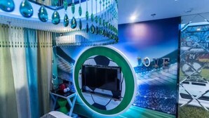 A room with a large circular window, a flat-screen TV, and a wall mural with a soccer field and the word 'LOVE'. - Mt Theme Hotel Shanghai (Shanghai)