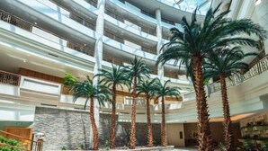 A multi-level atrium with palm trees, a stone wall, and a glass ceiling. - Palace Hotels (Chongqing Nanbin Road Holy Land Hot Spring Branch) (Chongqing)