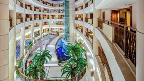 A multi-level hotel atrium with a central water feature, balconies, and indoor plants. - Palace Hotels (Chongqing Nanbin Road Holy Land Hot Spring Branch) (Chongqing)