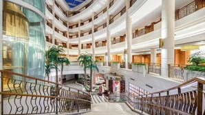A multi-level atrium with glass railings, palm trees, and a central staircase. - Palace Hotels (Chongqing Nanbin Road Holy Land Hot Spring Branch) (Chongqing)