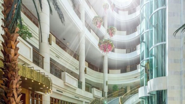 A multi-level atrium with a central staircase, palm trees, and hanging floral decorations. - Palace Hotels (Chongqing Nanbin Road Holy Land Hot Spring Branch) (Chongqing)