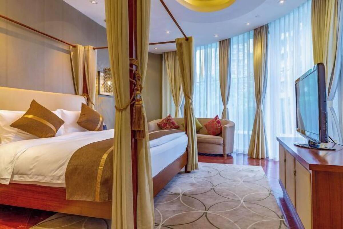 A hotel room with a large bed, a sofa, a TV, and a decorative curtain.