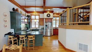 A spacious kitchen with a central island, wooden bar stools, and a stainless steel refrigerator.