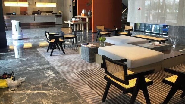 En moderne lobby med reception, siddeområde og et stort vindue.