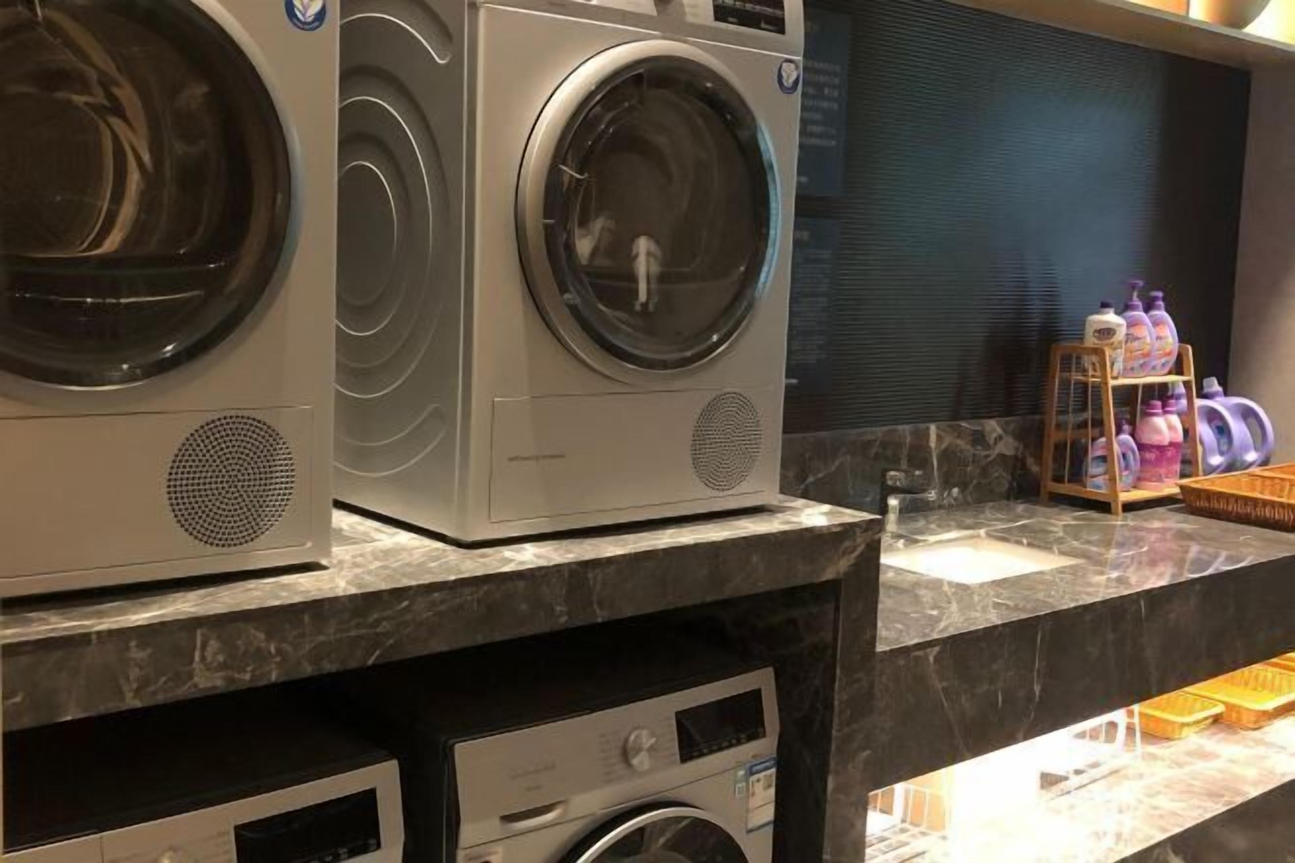 A laundry area with two stacked front-loading washing machines and a small sink.