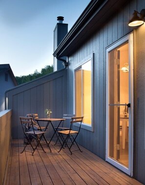 Une terrasse en bois avec une table et des chaises, une porte-fenêtre coulissante et une cheminée.