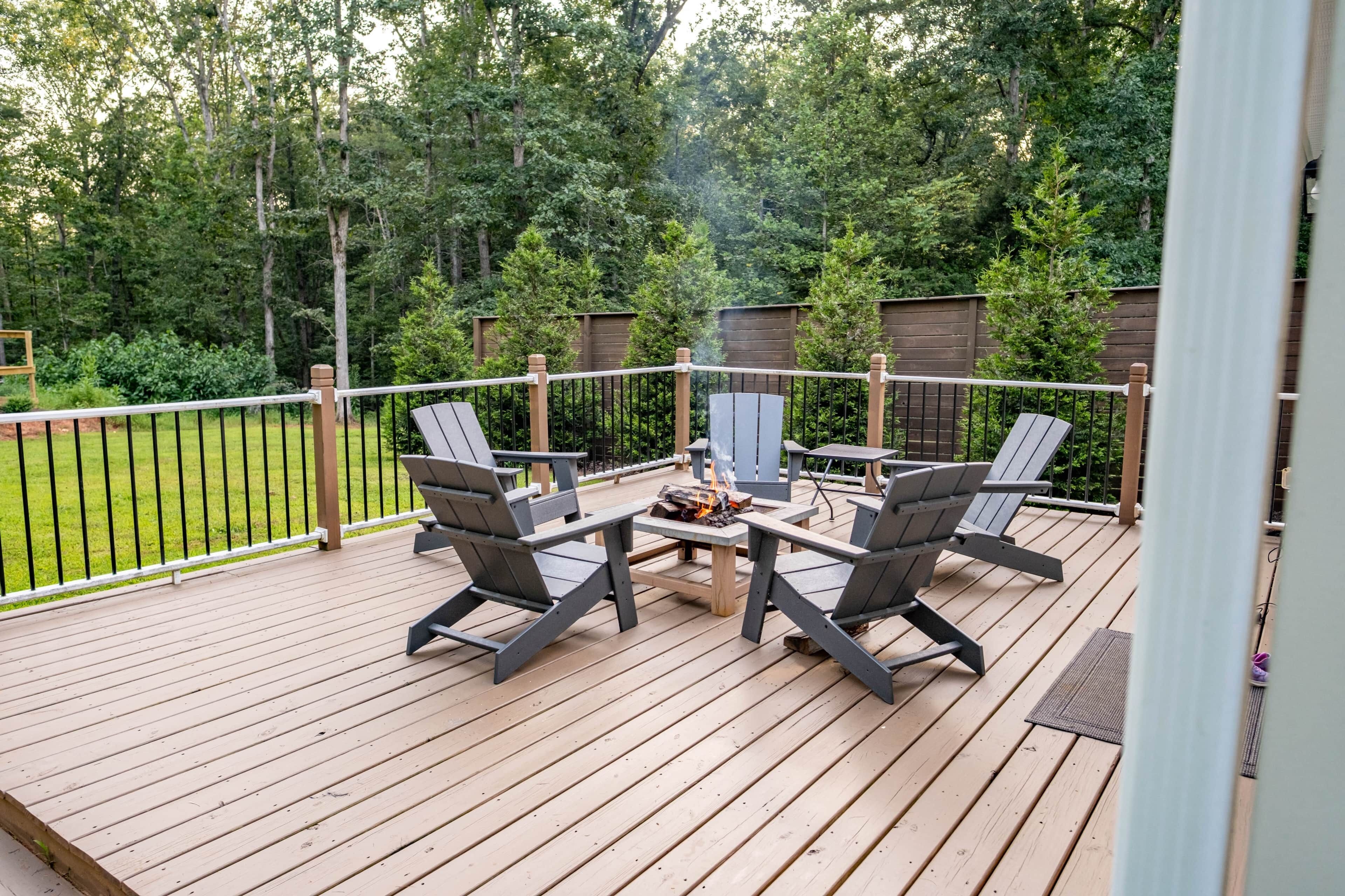 Eine Holzterrasse mit Feuerstelle und vier Stühlen.