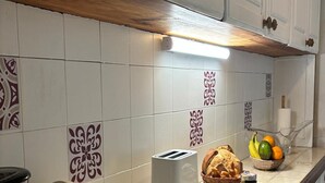 A kitchen with white cabinets, a toaster, a bread basket, a fruit bowl, and a coffee maker. - The breeze from Gros Morne to Deshaies (Deshaies)