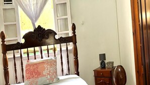 A bedroom with a wooden bed, a canopy, an air conditioner, and a wooden wardrobe. - The breeze from Gros Morne to Deshaies (Deshaies)