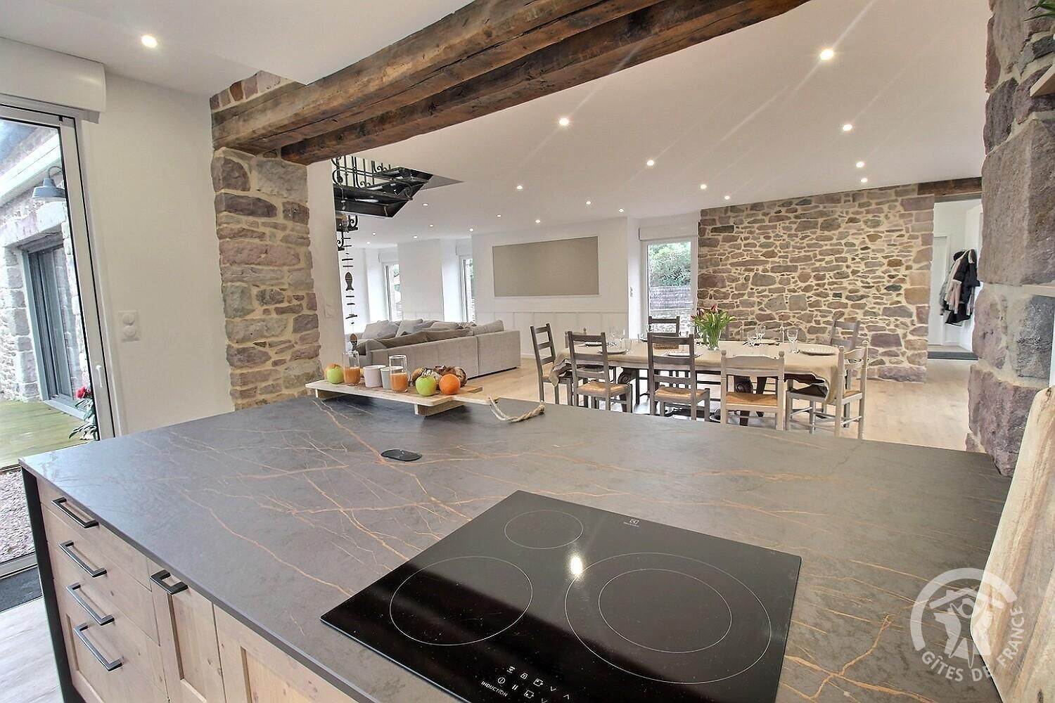 A modern kitchen with a stone accent wall, a built-in stove, and a dining area with a table and chairs.