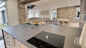 A modern kitchen with a stone accent wall, a built-in stove, and a dining area with a table and chairs.