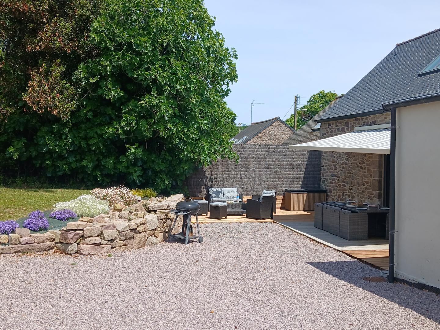 Un espacio al aire libre con mobiliario, una parrilla y un muro de piedra.