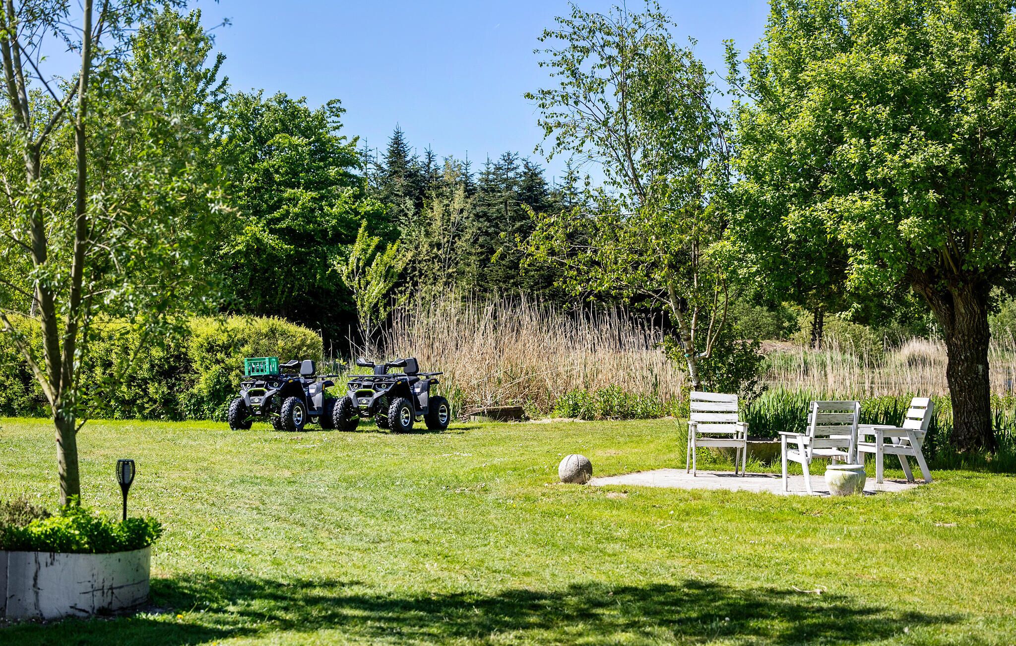 Ein Außenbereich mit geparkten Quads, einem Picknicktisch und einem großen Baum.