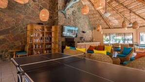 A room with a ping pong table, bookshelves, a television, and a stone wall with a dolphin mural. - 1 Bdrm, 2 Baths!!!! This is a larger 2 bdrm, chng'd to a 1 Bdrm!   MUCH LARGER!! (Cabo San Lucas)