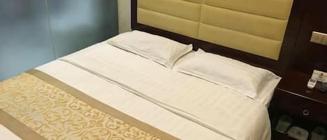 A hotel room with a bed, a headboard, a bedside table, and a nightstand.