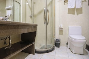 A bathroom with a glass shower enclosure, a white toilet, and a marble sink.