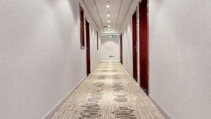 A hotel hallway with a patterned carpet, doors on both sides, and a ceiling with recessed lighting. - Super 8 (Beijing Yizhuang Kechuang Jiujie) (Beijing)