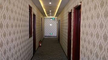A hallway with patterned wallpaper, doors, and a fire extinguisher.