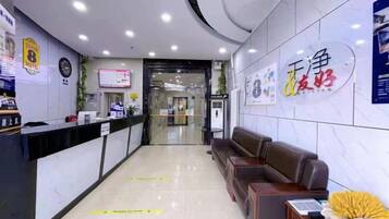 A hotel reception area with a reception desk, seating area, and a wall with signage.