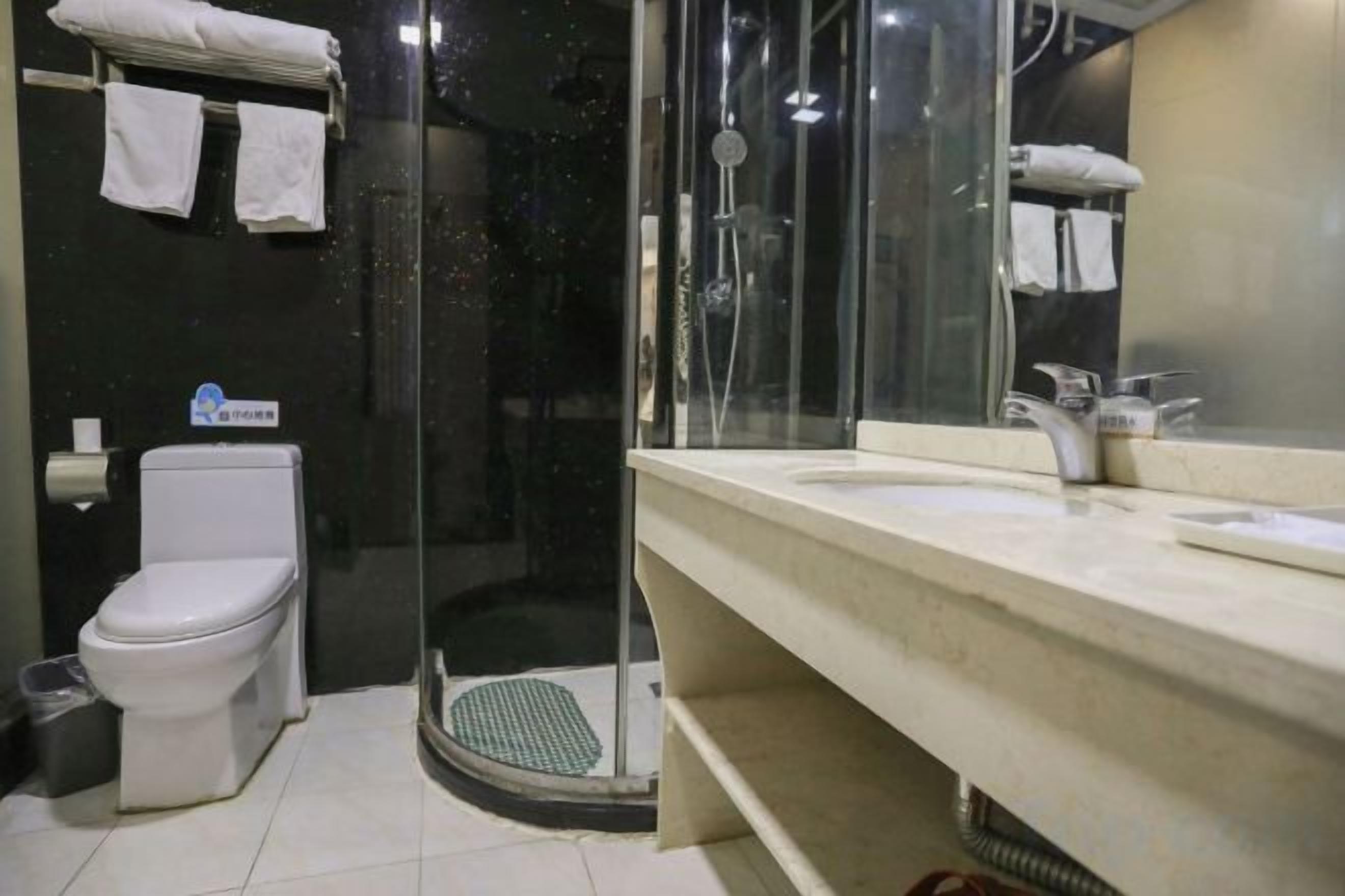 A bathroom with a toilet, a shower with a glass door, and a sink with a mirror.