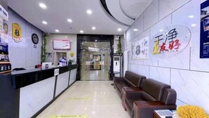 A hotel reception area with a reception desk, a brown leather sofa, and a wall with a sign. - Super 8 (Beijing Yizhuang Kechuang Jiujie) (Beijing)