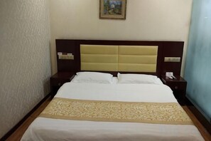 Quarto de hotel com cama grande, cabeceira, mesas de cabeceira e um quadro pendurado na parede.