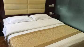 A hotel room with a large bed, a headboard, a bedside table, and a wall-mounted phone.