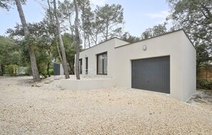 Ein modernes Gebäude mit einem Schotterweg, einer Garage und einer Terrassenfläche.