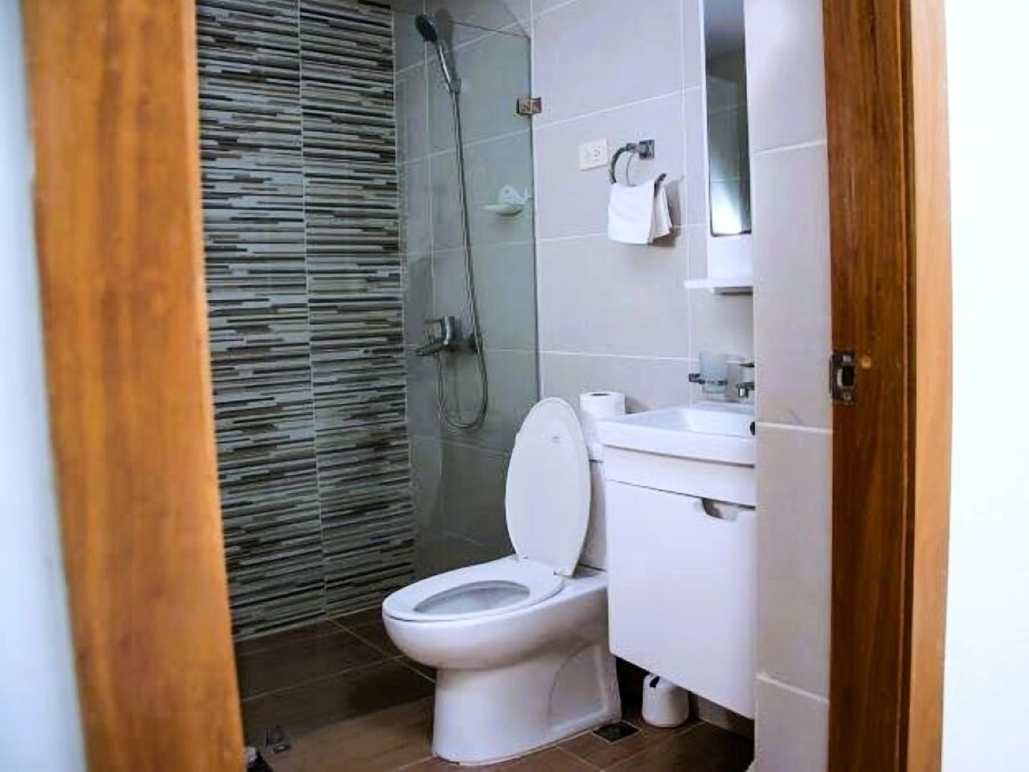 Een moderne badkamer met een douchecabine van glas, een wit toilet en een wastafel met een spiegel erboven.