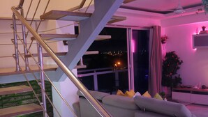 A modern interior with a staircase, a grey sofa, and a plant. - Sejour's Penthouse (Santo Domingo Este)