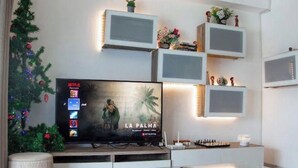 A modern living room with a flat-screen TV, a glass coffee table, and a decorative Christmas tree. - Sejour's Penthouse (Santo Domingo Este)