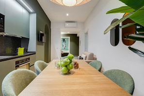A modern kitchen with a wooden dining table, chairs, and a fruit bowl.