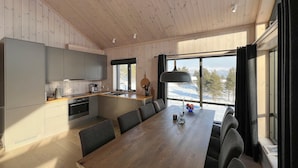 A modern kitchen with a wooden table and chairs, large windows with a view of a snowy landscape, and a pendant light. - Gorgeous home in Kvam with sauna (Kvam)