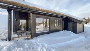A wooden cabin with large windows and a thatched roof, surrounded by snow. - Gorgeous home in Kvam with sauna (Kvam)
