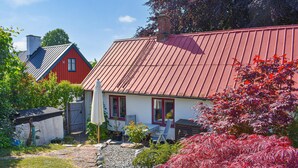 Ein Haus mit rotem Dach, ein Garten mit roten Blättern und ein klarer Himmel.