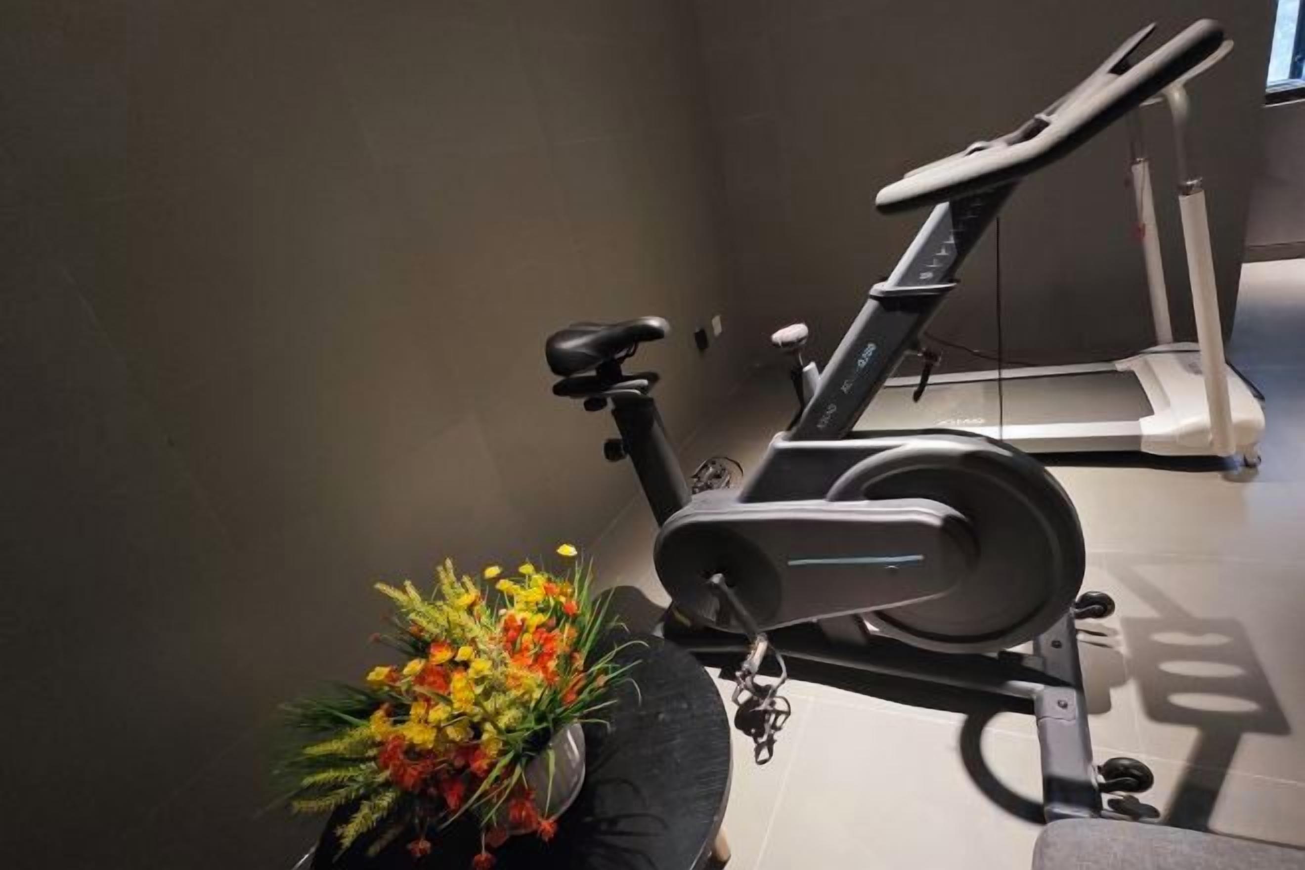 A stationary bike with a floral arrangement beside it.
