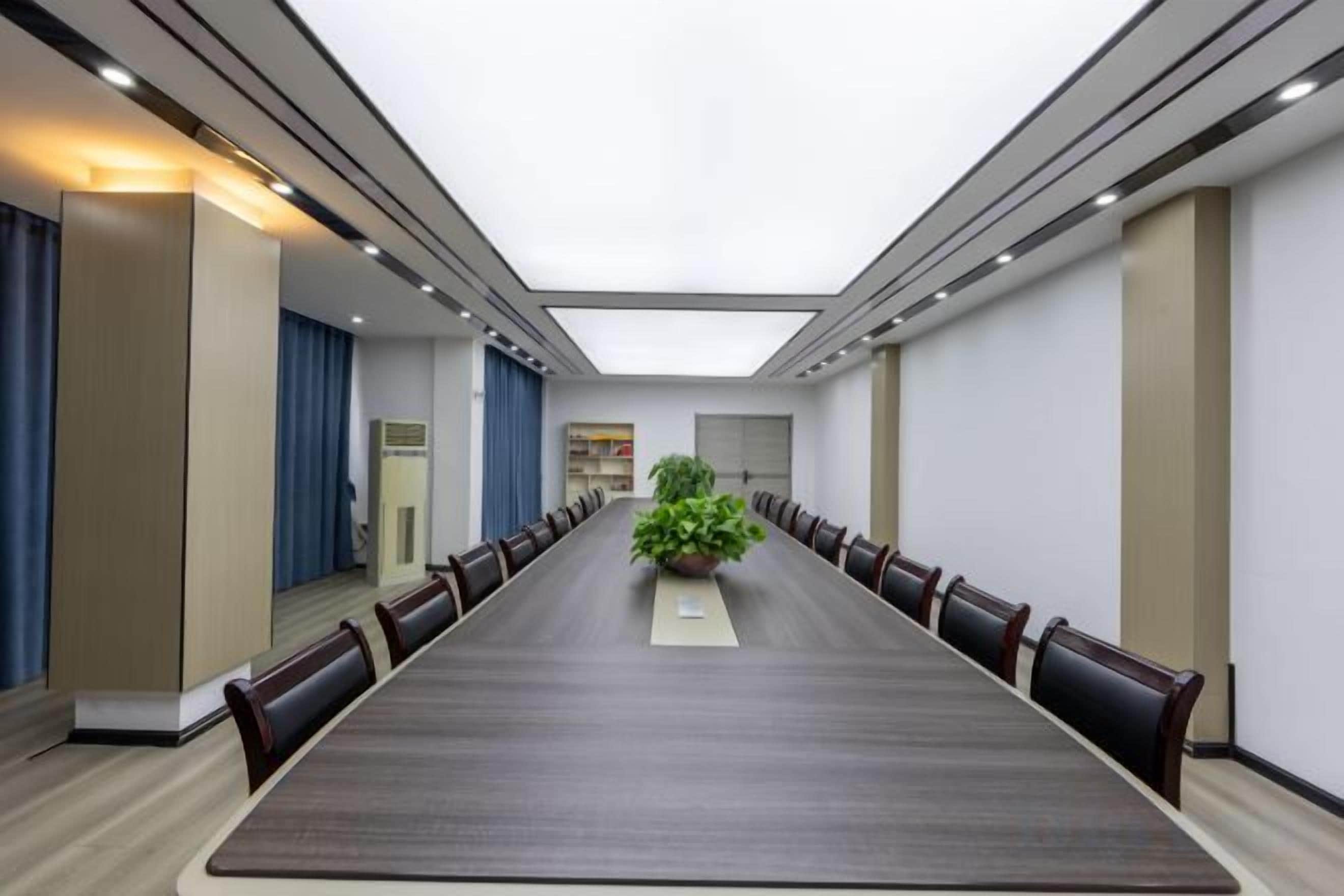 Un salón de conferencias con una mesa larga, sillas y un centro de mesa con planta.