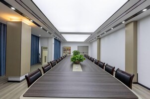 Un salón de conferencias con una mesa larga, sillas y un centro de mesa con planta.